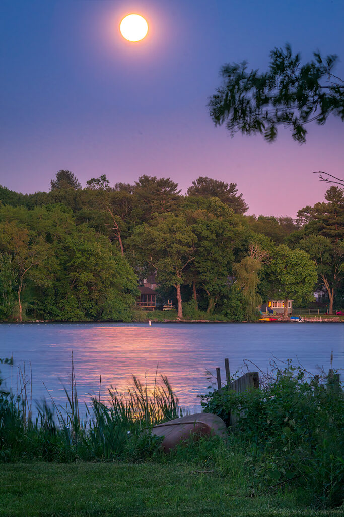 Full moon over smooth glossy water in the lake